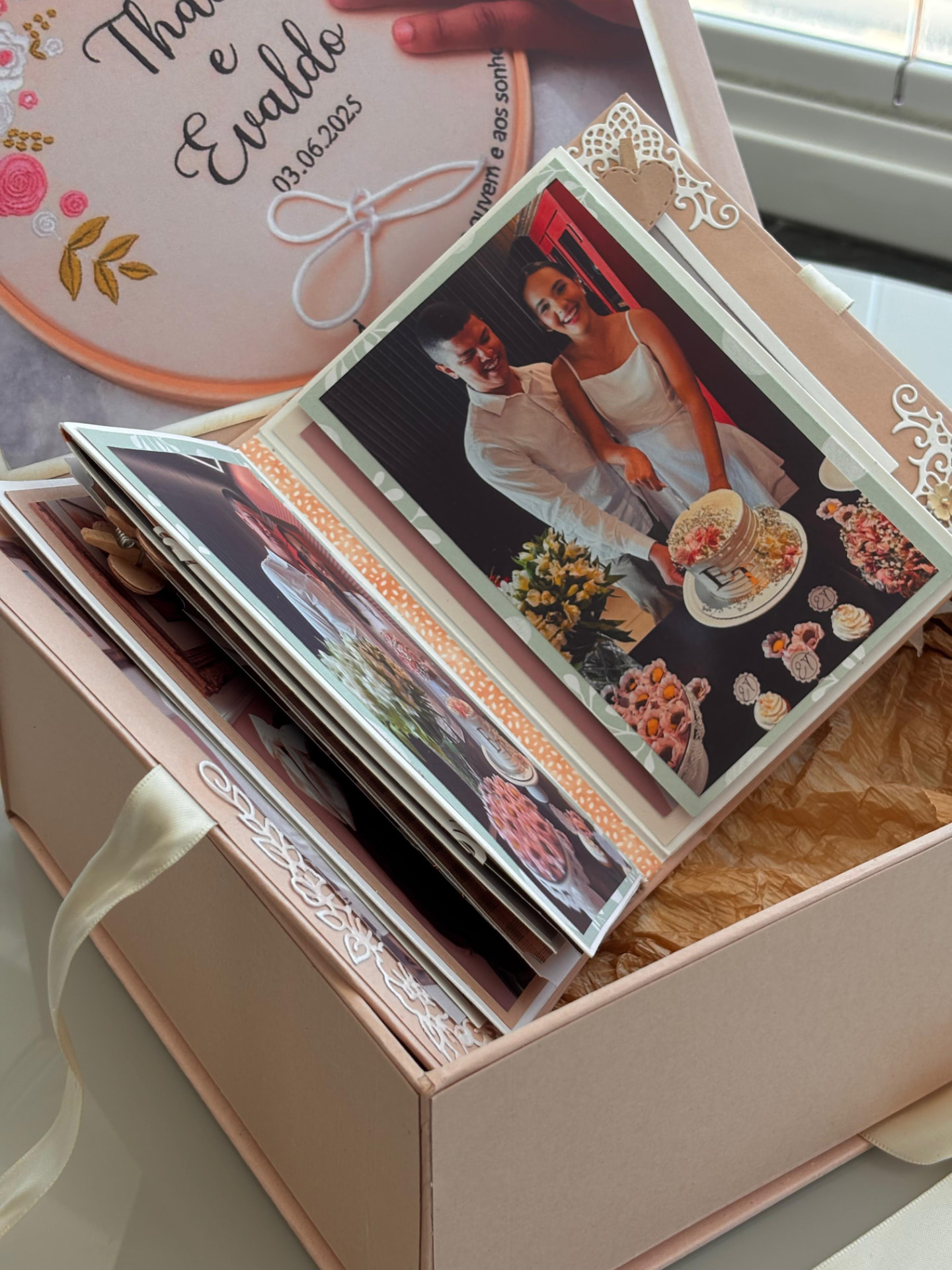 Álbum de casamento aberto com fotos e decoração em renda branca