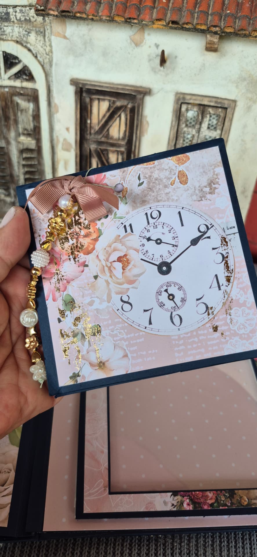 Página de álbum com estampa de relógio antigo, flores rosadas e pingente de pérolas