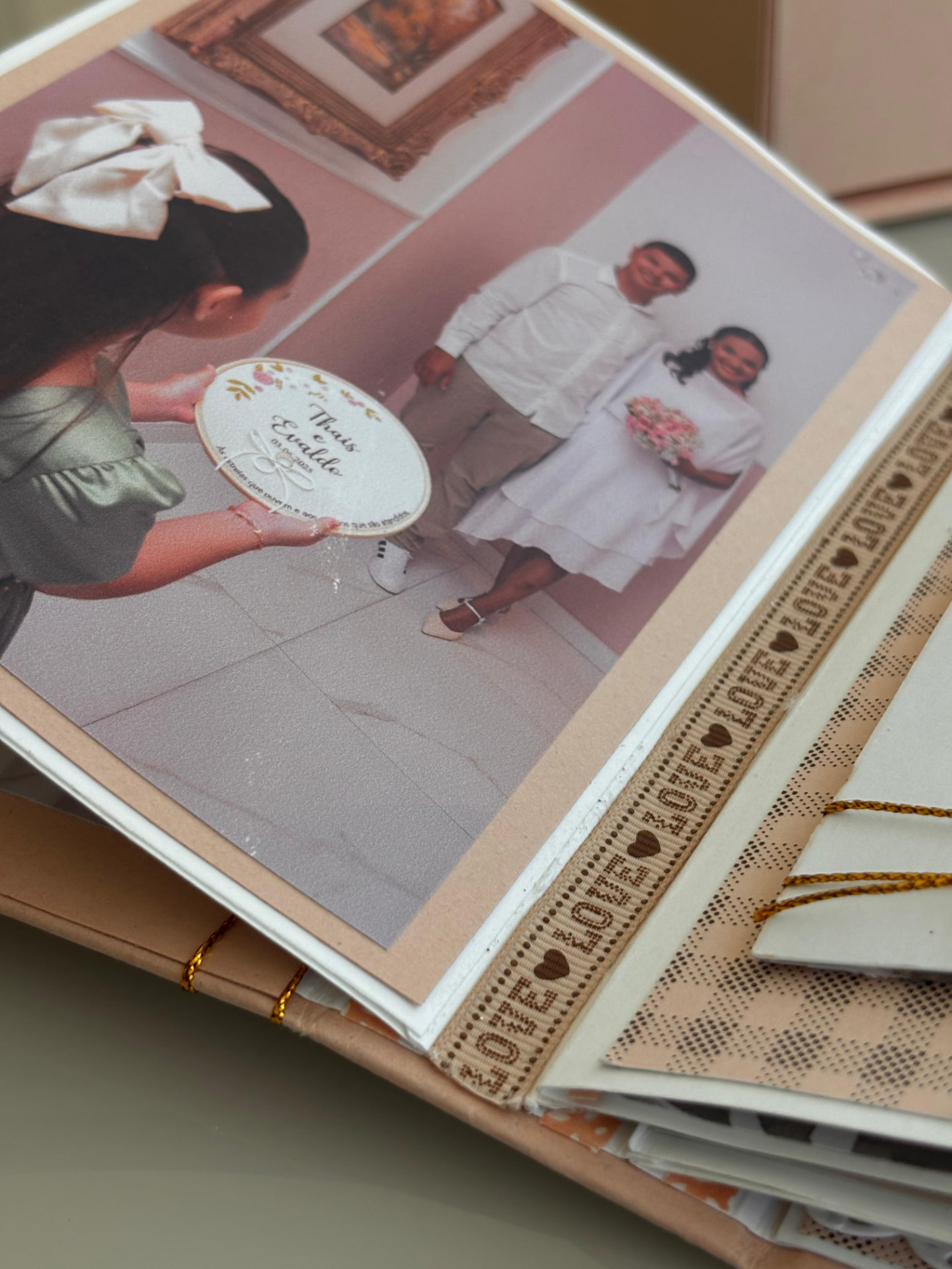 Close de página do álbum com foto de casamento e fita decorativa com a palavra Love