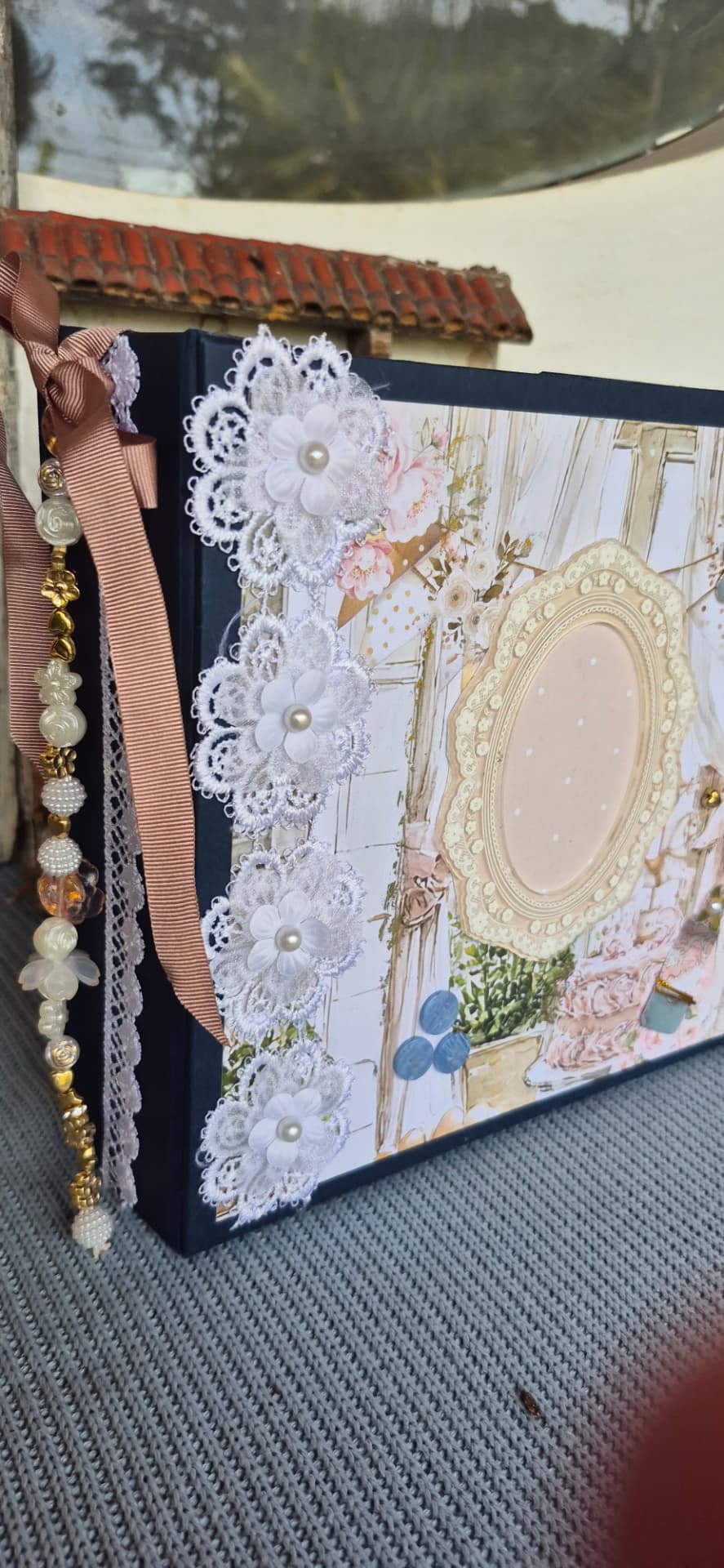 Álbum azul decorado com flores de renda branca, fita pêssego e capa ilustrada